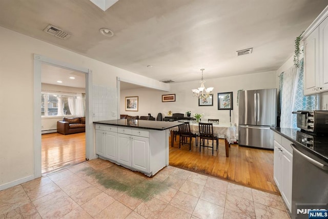 kitchen with stainless steel appliances, dark countertops, visible vents, and a baseboard radiator