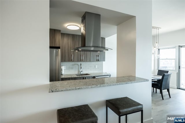 kitchen with island range hood, a sink, freestanding refrigerator, decorative backsplash, and modern cabinets