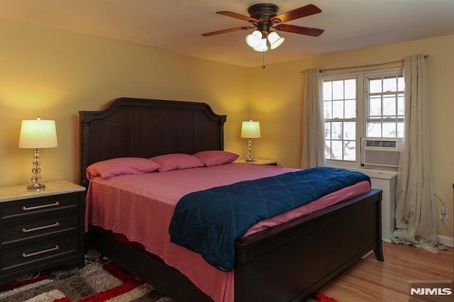 bedroom with light wood-style floors, cooling unit, and a ceiling fan