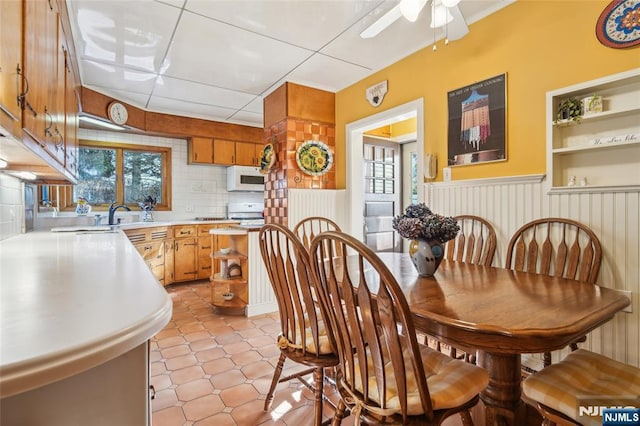 dining room with crown molding, a ceiling fan, and wainscoting