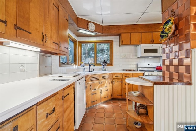 kitchen with white appliances, backsplash, brown cabinets, and open shelves