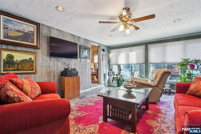 living area featuring baseboard heating, a textured ceiling, and a ceiling fan