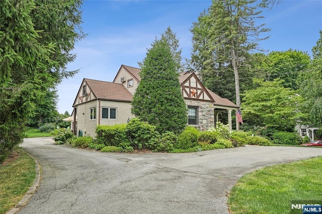 tudor house featuring stone siding and a shingled roof