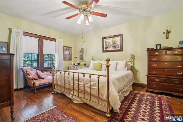 bedroom featuring baseboards, dark wood finished floors, and a ceiling fan