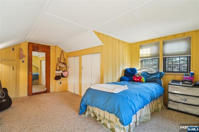 carpeted bedroom featuring a closet, lofted ceiling, and wooden walls