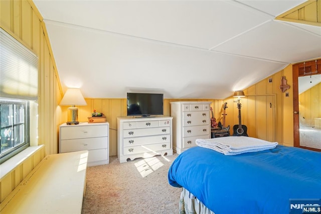 carpeted bedroom with lofted ceiling and wooden walls