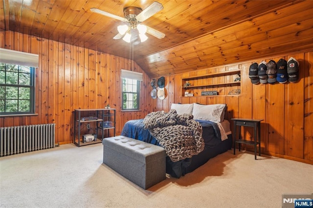 carpeted bedroom with multiple windows, radiator heating unit, wood ceiling, and wood walls