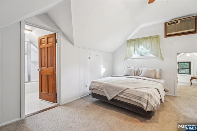 carpeted bedroom featuring connected bathroom, lofted ceiling, an AC wall unit, and a ceiling fan