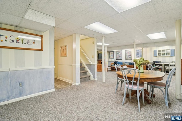 dining space featuring stairway, carpet flooring, a paneled ceiling, and baseboards