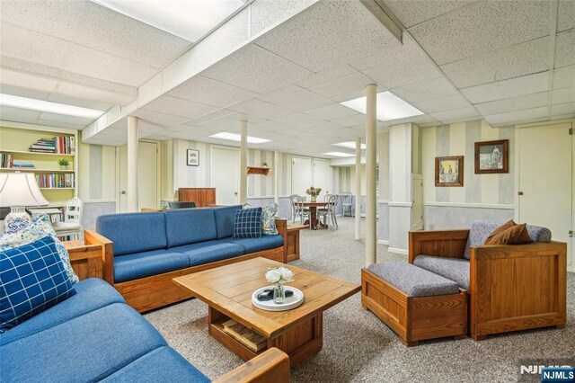 living area featuring a paneled ceiling and carpet