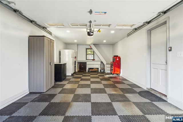 garage featuring recessed lighting, a garage door opener, baseboards, and freestanding refrigerator