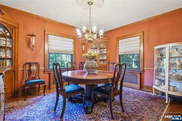 dining room featuring a notable chandelier, a healthy amount of sunlight, wood finished floors, and ornamental molding