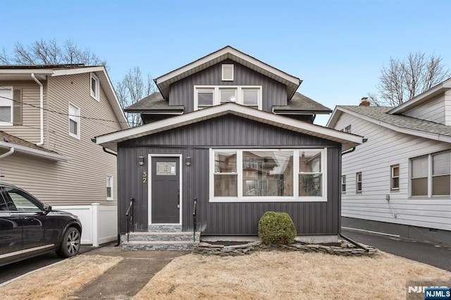 view of front facade with entry steps, a shingled roof, and board and batten siding