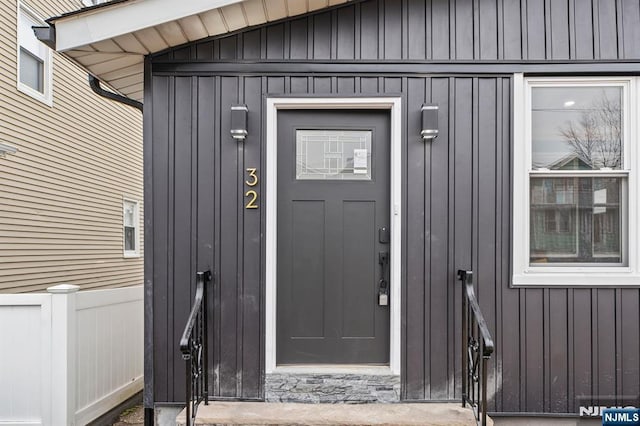 view of exterior entry featuring fence and board and batten siding