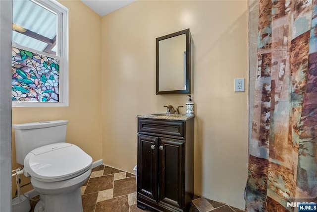 bathroom with toilet, vanity, and stone tile floors