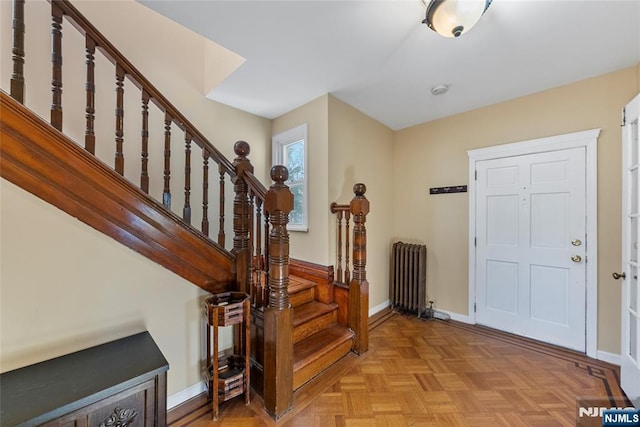 entryway featuring radiator heating unit, stairs, and baseboards