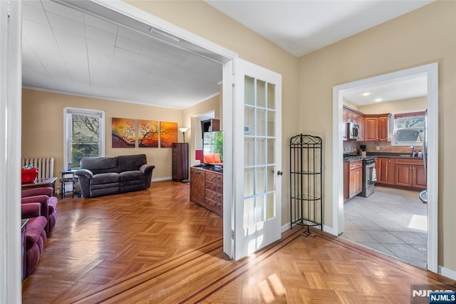 doorway to outside with baseboards, a sink, and radiator heating unit