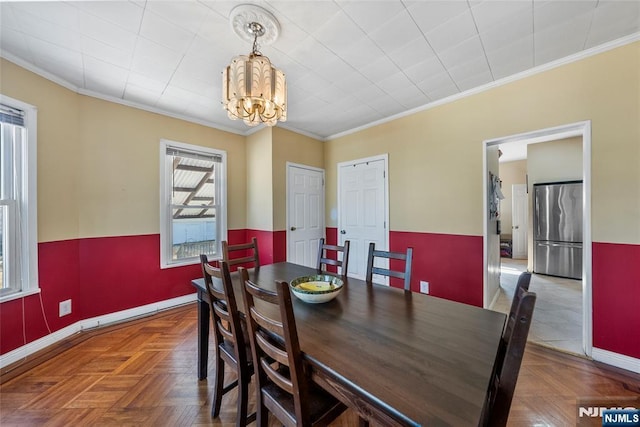 dining space featuring baseboards, ornamental molding, and a notable chandelier