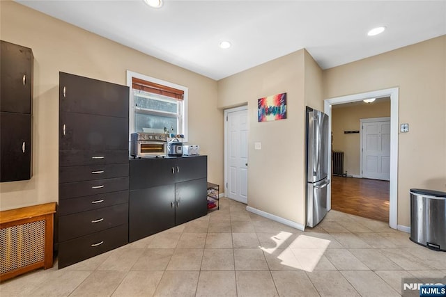 kitchen with light tile patterned floors, recessed lighting, radiator, freestanding refrigerator, and baseboards