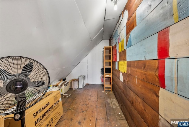 interior space featuring lofted ceiling, hardwood / wood-style floors, and wooden walls