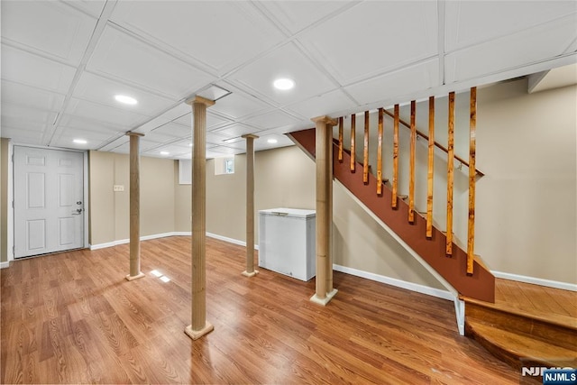 finished basement featuring fridge, stairway, baseboards, and wood finished floors