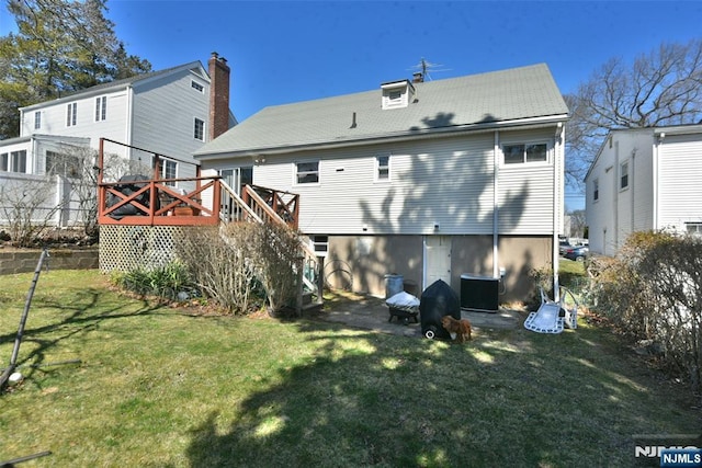 rear view of house with a deck, central AC unit, a yard, and fence