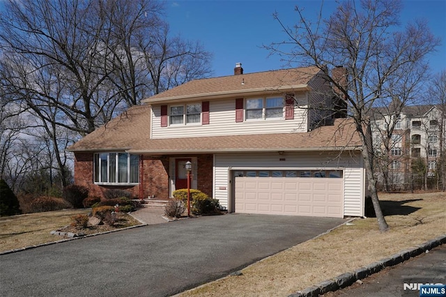 tri-level home featuring aphalt driveway, brick siding, a chimney, a shingled roof, and an attached garage