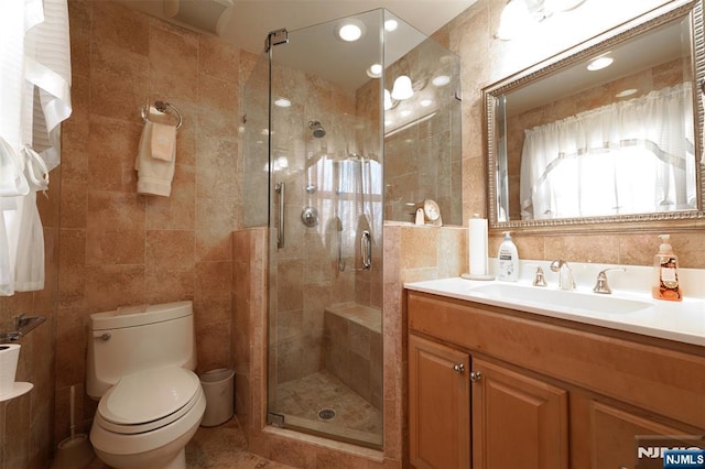 full bathroom featuring toilet, a stall shower, tile walls, and vanity