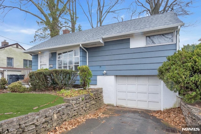 single story home with a shingled roof, a chimney, and a garage