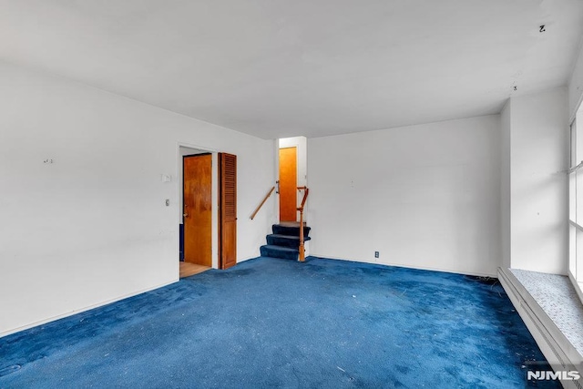 unfurnished room with stairs and carpet flooring