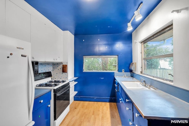 kitchen featuring freestanding refrigerator, a sink, blue cabinetry, and gas range oven