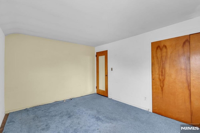 spare room featuring carpet floors and vaulted ceiling