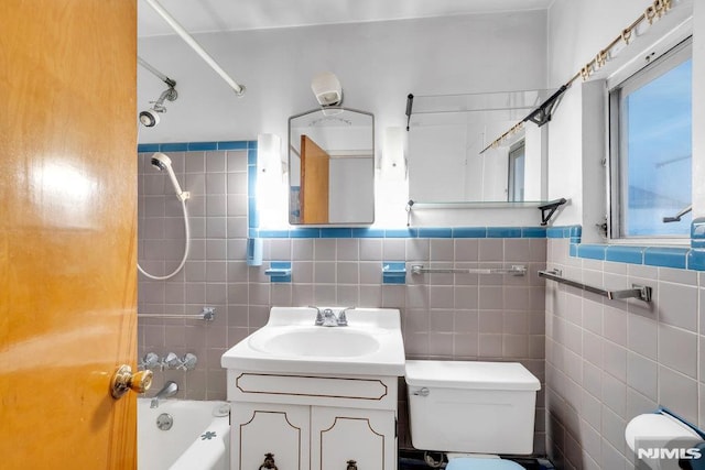 full bathroom featuring vanity, shower / tub combination, toilet, and tile walls