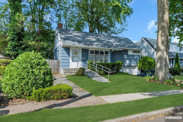 view of front facade featuring roof with shingles, a chimney, and a front yard