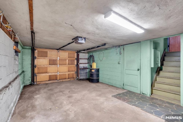 garage featuring concrete block wall and a garage door opener