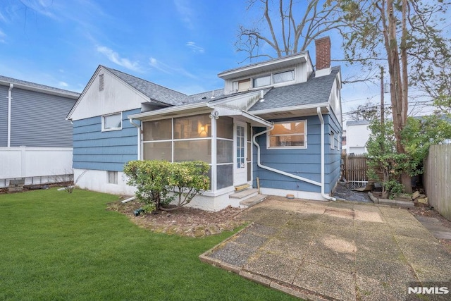 back of house with a fenced backyard, a sunroom, a yard, a chimney, and a patio area