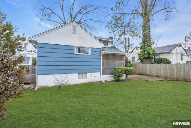 back of house featuring a sunroom, a lawn, a chimney, and fence