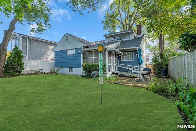 rear view of property featuring a fenced backyard, a chimney, and a lawn