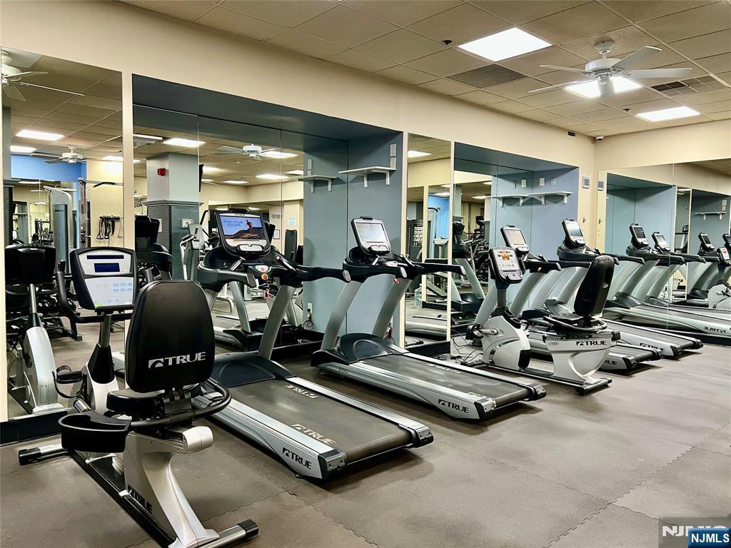 exercise room featuring a drop ceiling, visible vents, and a ceiling fan