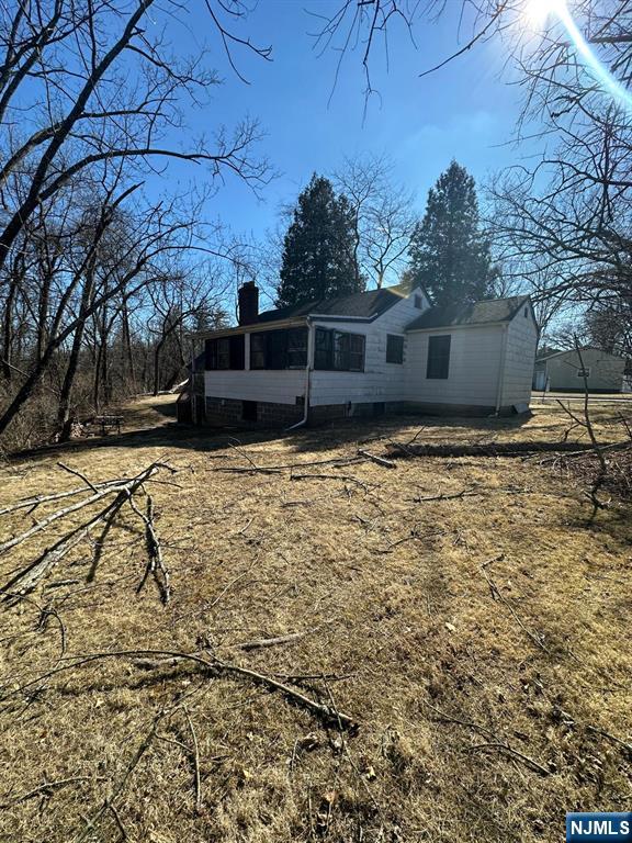 rear view of property featuring a sunroom and a chimney