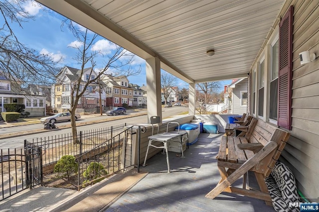 view of patio / terrace featuring a residential view, covered porch, and fence