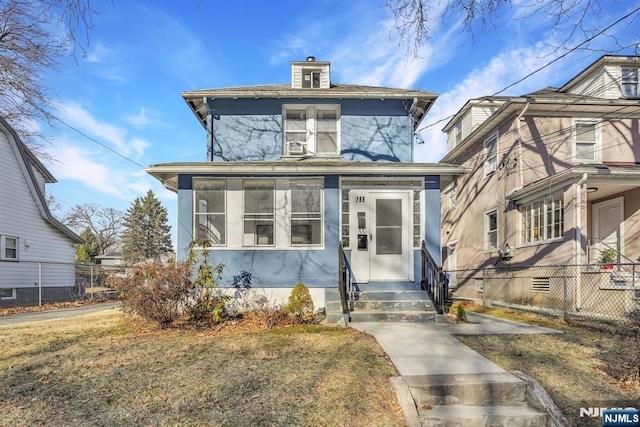 american foursquare style home featuring fence and a front lawn