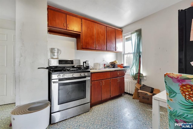 kitchen with stainless steel gas stove, radiator, brown cabinets, and light countertops