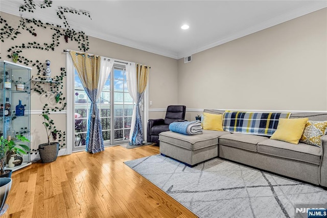 living area with visible vents, crown molding, and wood finished floors