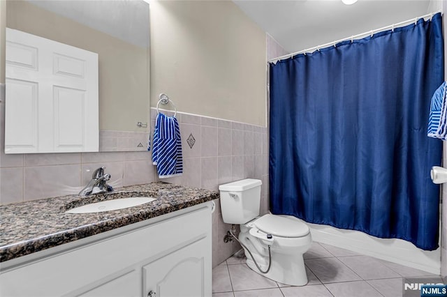 bathroom featuring toilet, tile patterned flooring, shower / bathtub combination with curtain, vanity, and tile walls