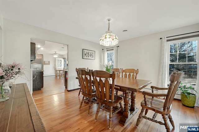 dining space with baseboards and light wood-style flooring