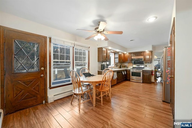 dining space with light wood-style flooring, a toaster, a ceiling fan, and a baseboard radiator