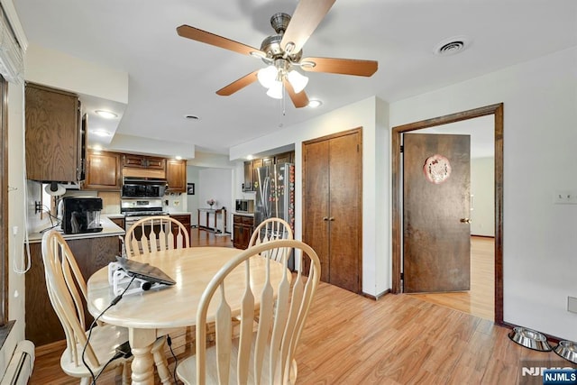 dining space with visible vents, light wood-style flooring, baseboards, baseboard heating, and ceiling fan