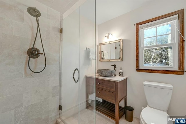 bathroom featuring tile patterned floors, a stall shower, toilet, and vanity