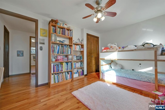 bedroom with a ceiling fan, wood finished floors, and baseboards